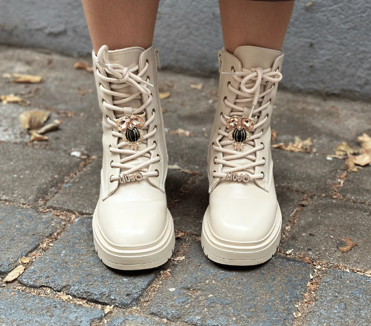 White combat boots on a person standing on a stone pavement.